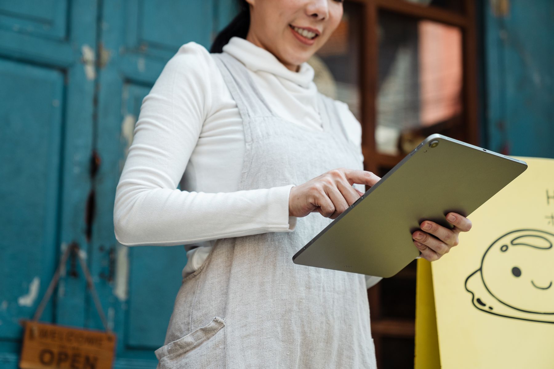 Business operator using a tablet outside a storefront while managing day-to-day operations
